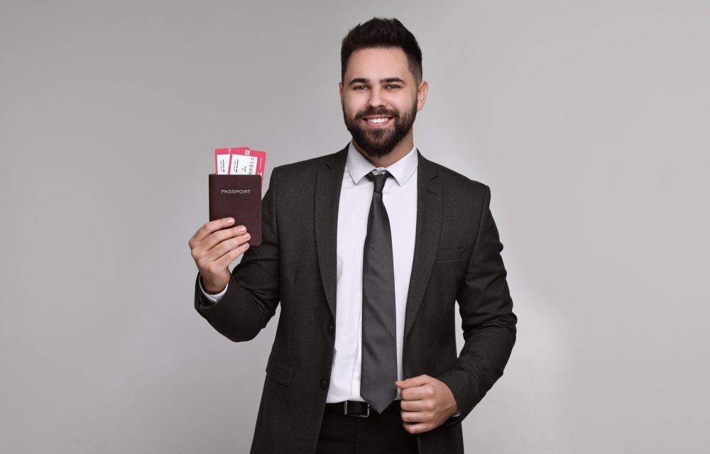 Happy businessman with passport and tickets on grey background